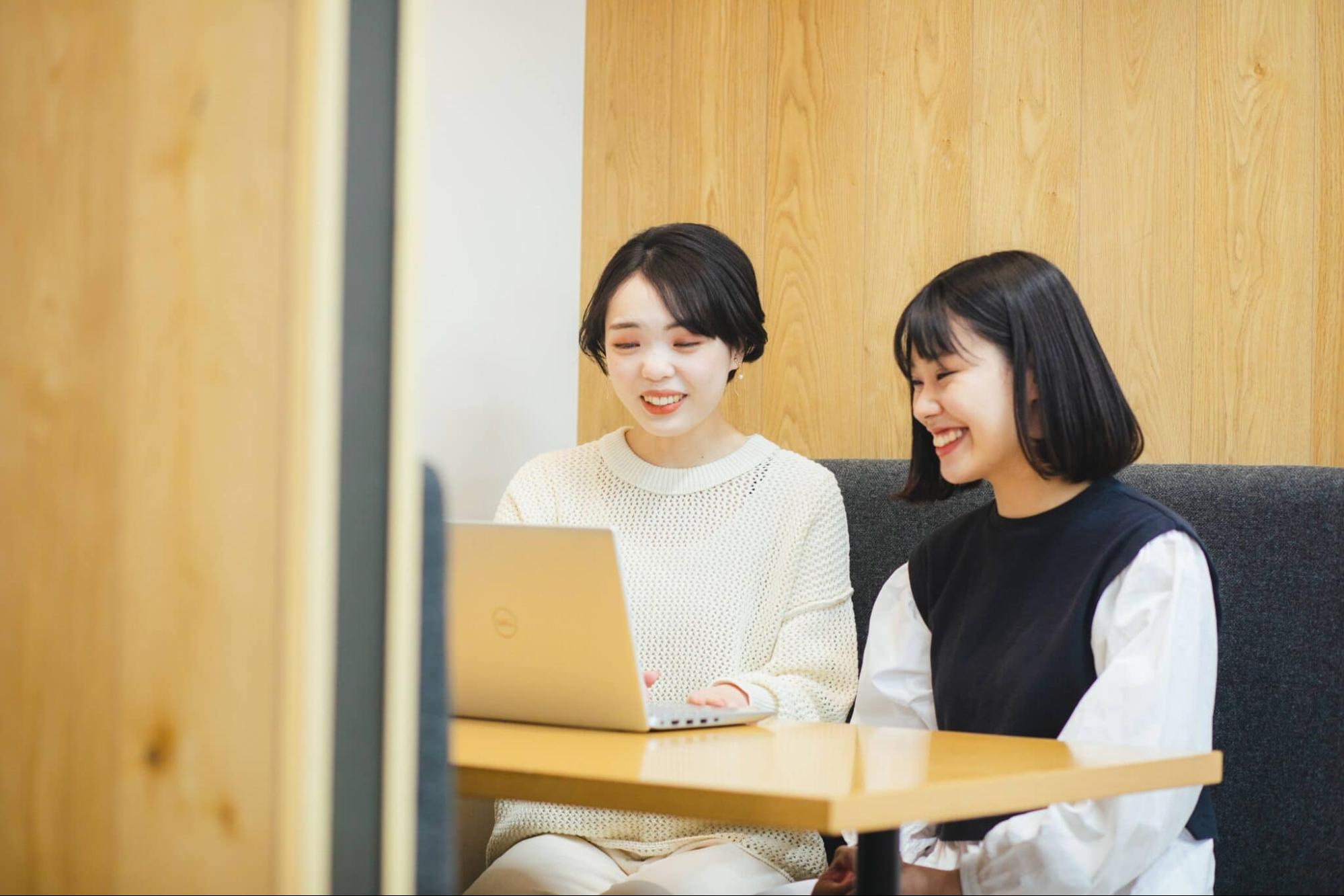 パソコンの画面を見ながら笑い合う女性2人